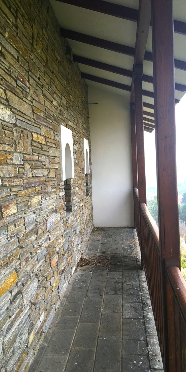 Traditional stone balcony with wooden frame looking out onto a rural view